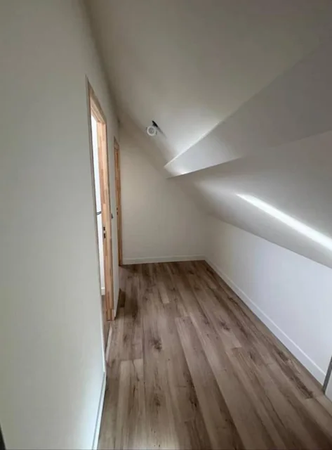 Espace sous pente avec murs blancs et sol aspect bois